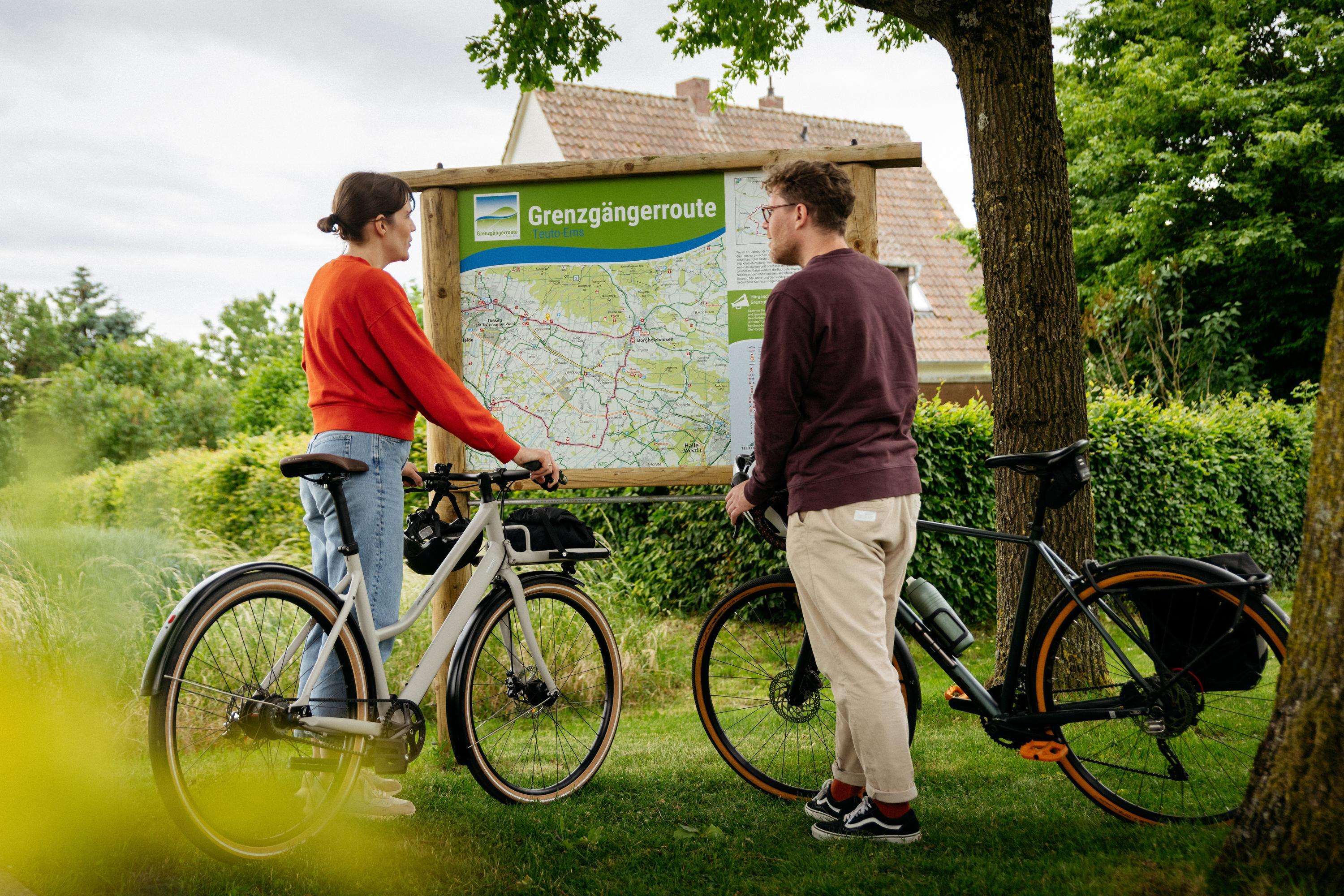 Radfahrer an einer Infotafel der Grenzgaengerroute Teuto-Ems